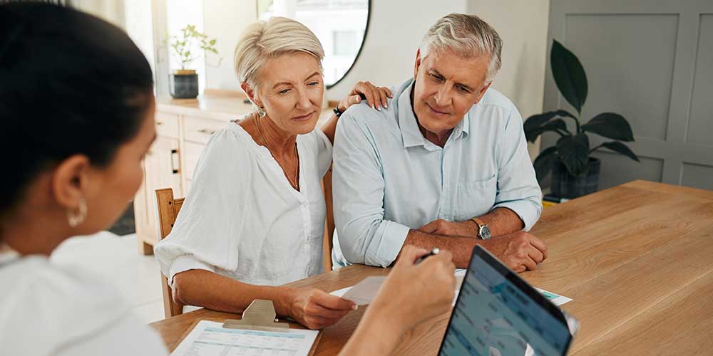 Middle aged couple viewing information on a laptop during a meeting